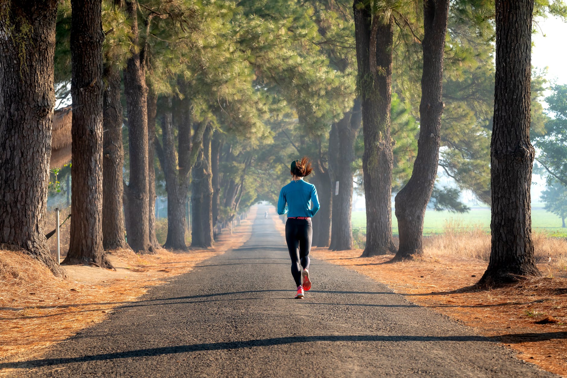 a woman in black leggings running on a concrete road