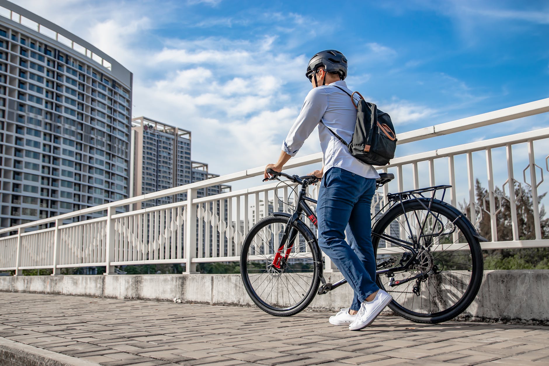 man in long sleeves walking his bike