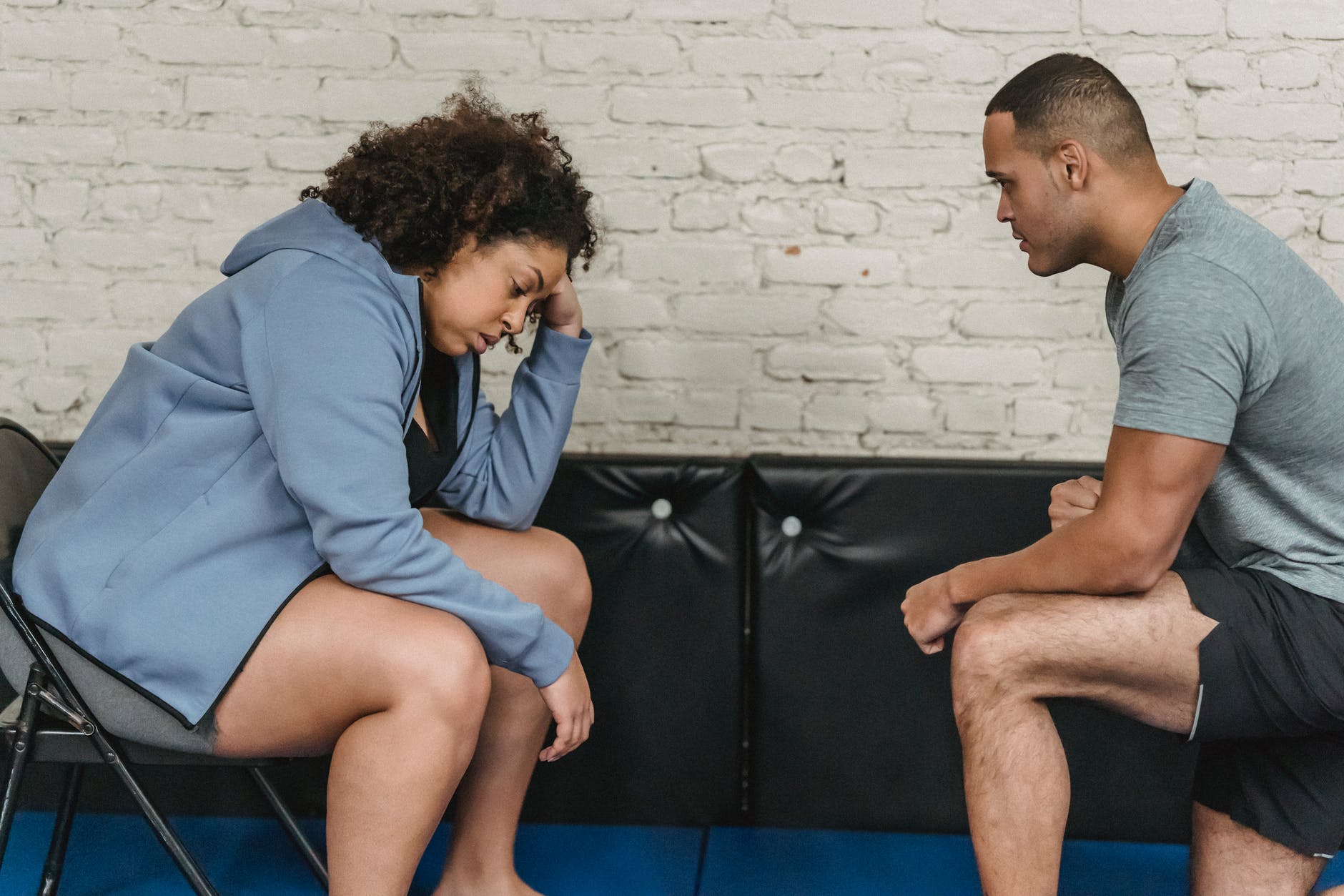 tired black woman with trainer in gym