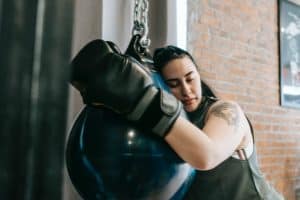 tired woman in boxing gloves resting after training