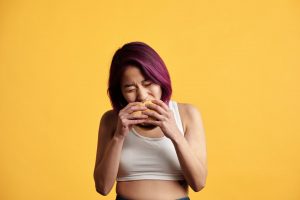 colored hair woman eating hamburger