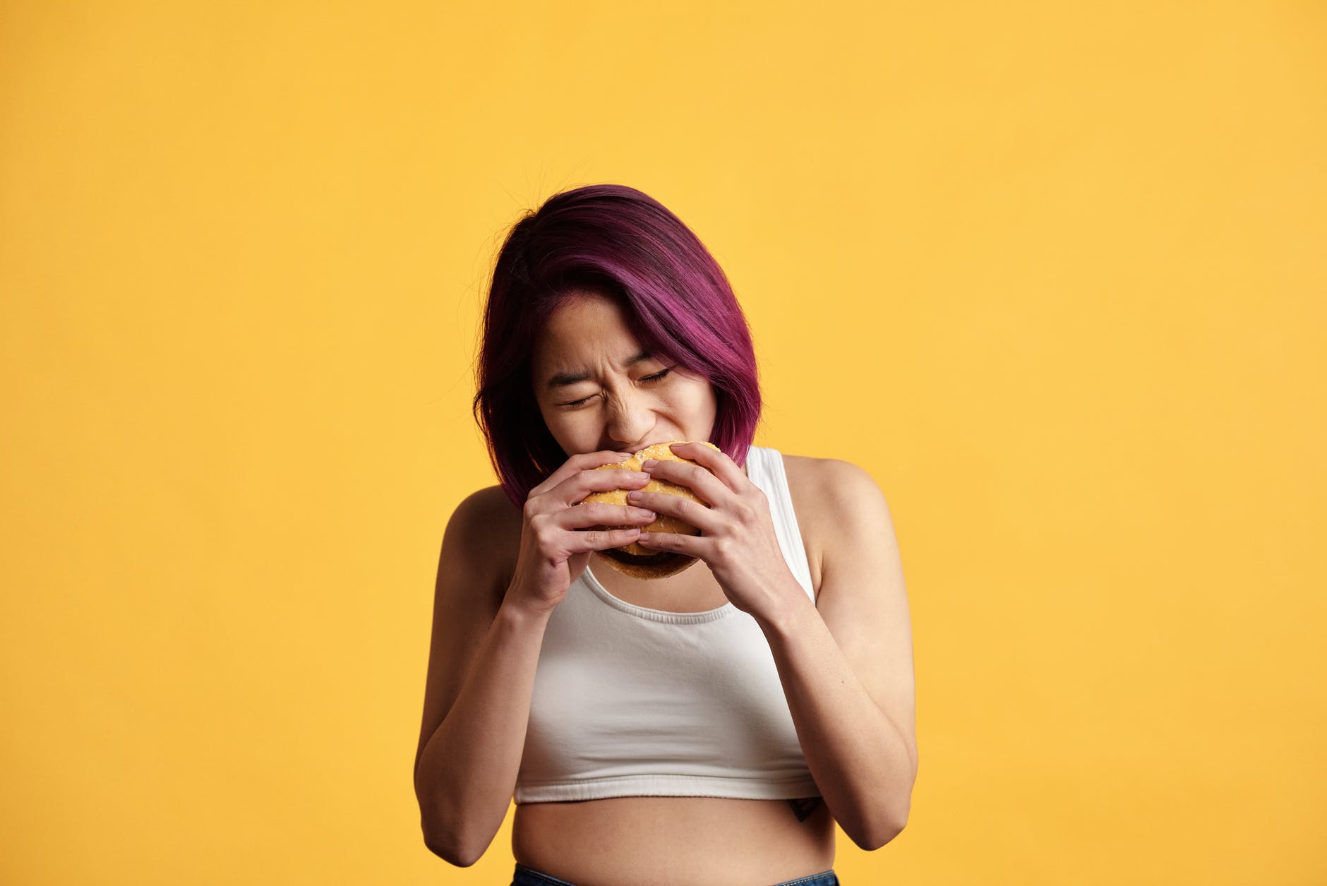 colored hair woman eating hamburger