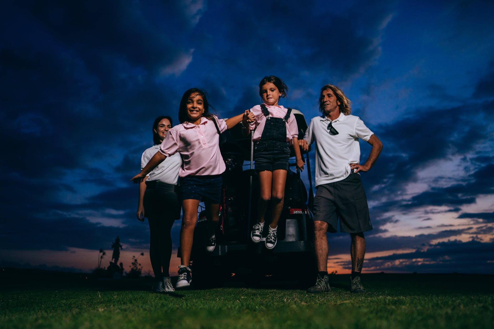 family on green grass field under dark blue sky