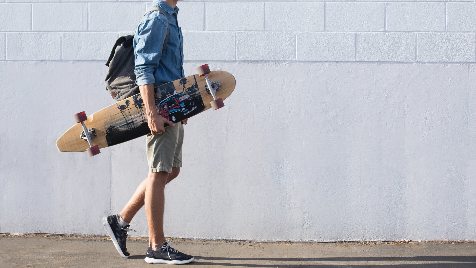 man in blue top carrying a longboard