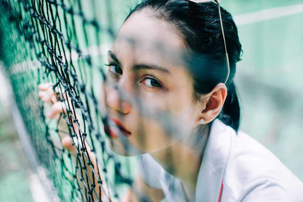 young woman in sportswear behind net