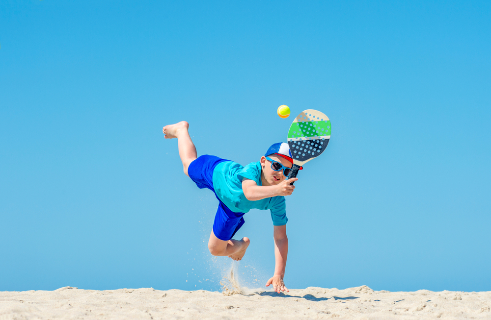 Enfant qui joue à la raquette à la plage